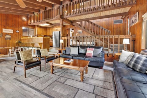 Cozy mountain living room with wood ceilings, stone fireplace, comfy seating —perfect for relaxing evenings, movie nights, and warm cabin vibes after outdoor adventures.