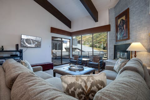 Sink into plush sofas by your crackling fireplace, where mountain views through floor-to-ceiling windows create the perfect alpine retreat backdrop.