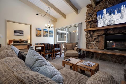 Sink into plush sofas by your stone fireplace, where winter artwork and exposed beams create the perfect alpine retreat atmosphere.
