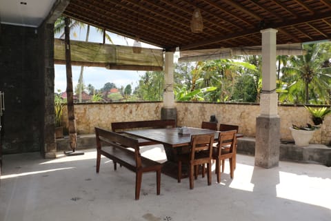 An outdoor dining area with rice fields and pool view
