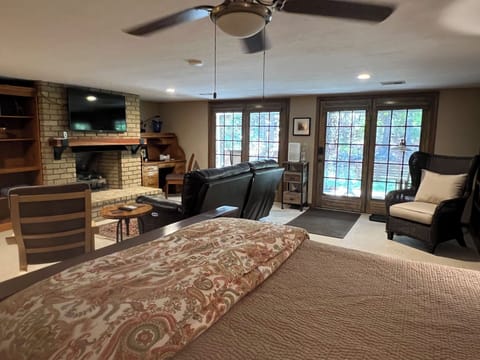 View from bed of TV, gas fireplace, couch, desk, the patio and woods.