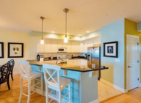 Kitchen w/ oven, microwave, dishwasher, & fridge.  Counter stools at the island.