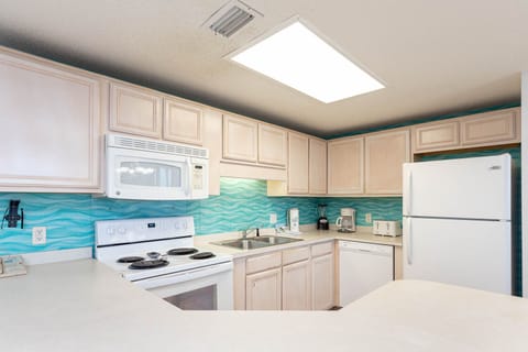 Prepare meals in this kitchen, featuring aqua wave backsplash, ample counter space, and white appliances