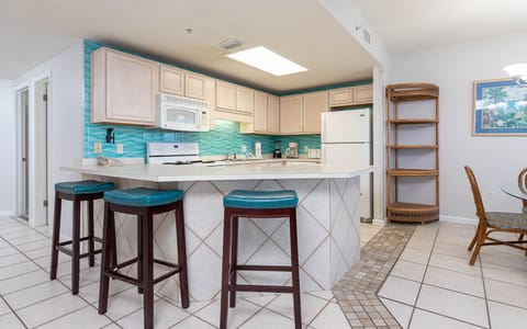 Enjoy cooking in this cheerful kitchen with turquoise accents, white appliances, and a convenient breakfast bar