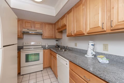 This kitchen features light wood cabinetry, granite countertops, and a full set of appliances, perfect for meal prep