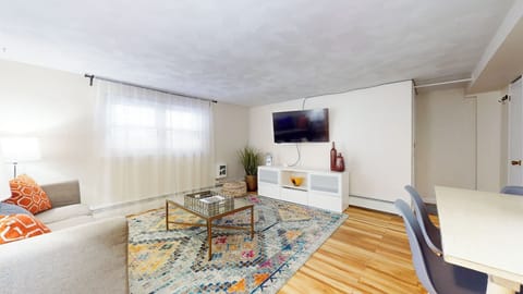 Bright and cozy living area featuring a stylish sectional sofa, a wall-mounted TV