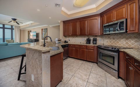 This inviting kitchen features rich wood cabinetry, granite countertops, stainless appliances, and a view of the beach