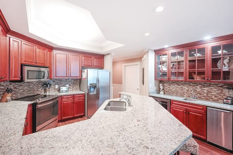 The kitchen features rich cherry cabinetry, stainless appliances, spacious granite countertops, and elegant backsplash