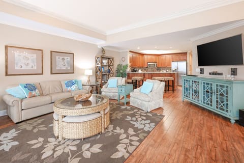 This cozy living area features a large TV with speakers, and comfortable seating, perfect for relaxation and entertainment