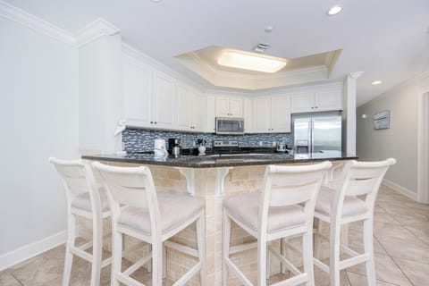 Modern kitchen with granite countertops, stainless appliances, and comfortable bar seating for casual dining