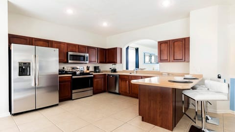 Spacious kitchen with stainless steel appliances, bar seating, and rich wood cabinets!