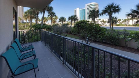 Relax on the guest room balcony with comfortable seating, surrounded by lush greenery and views of the nearby palm trees