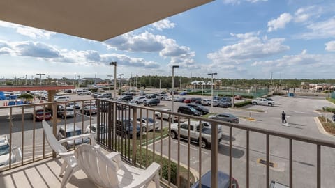 The master balcony view showcases a bustling parking lot with a mix of cars and a glimpse of nearby recreational facilities