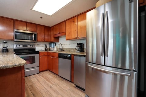 The kitchen features rich wood cabinetry, granite countertops, and stainless appliances, creating a warm and functional space