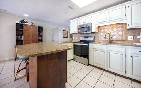 Prepare meals in the spacious kitchen featuring a large countertop, stainless appliances, and a stylish backsplash