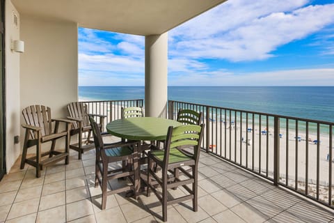 Enjoy dining on this sixth-floor balcony with green chairs and a table, overlooking the beautiful beach and lazy river