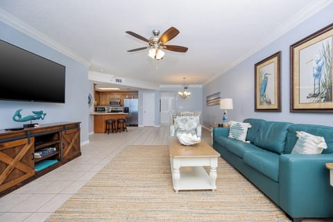 Inviting living space with a comfortable sofa with queen sleeper, large TV, and a view into the kitchen and dining area