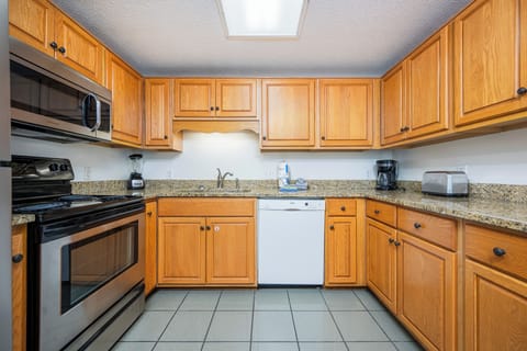 Prepare meals in the spacious kitchen featuring wooden cabinets, granite countertops, and stainless appliances