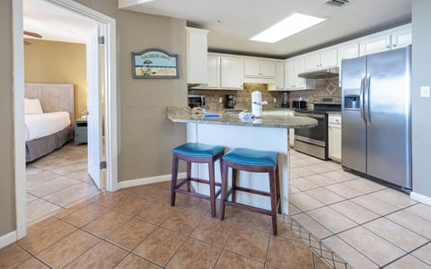 Gather around the breakfast bar with teal stools, enjoying easy access to the kitchen and a cozy master bedroom view