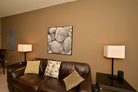 Living room has a leather couch and original art