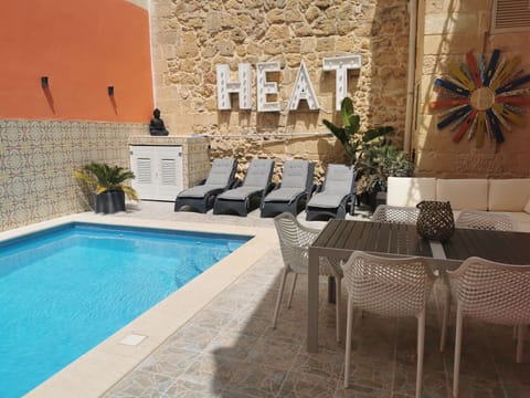 sunny private swimming pool with couch and dining area