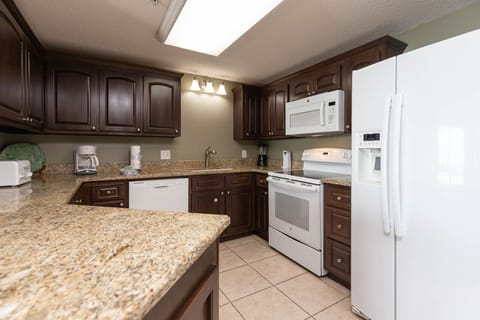 Cook and gather in this spacious kitchen featuring dark wood cabinets, granite countertops, and white appliances