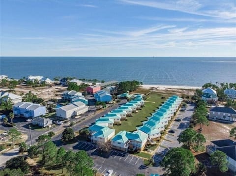 Gulf front complex, swimming pool, large grassy outdoor space, sandy beach area.