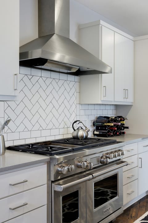 Cook your favorite meals on professional-grade appliances with elegant white cabinetry and herringbone tile backsplash surrounding you.