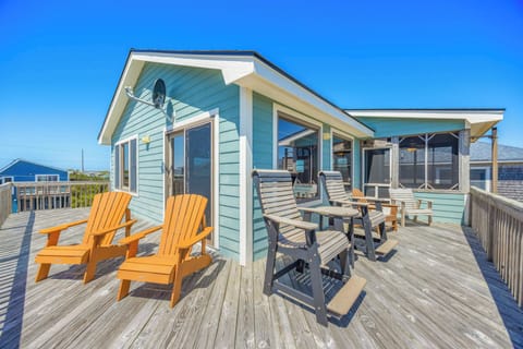 This charming aqua-blue beach cottage with its spacious deck offers the perfect outdoor retreat. Relax in vibrant Adirondack chairs or gather around the dining table for meals with ocean breezes.