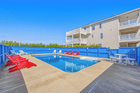 A spacious private pool awaits, lined with colorful lounge chairs and surrounded by a bright blue privacy fence—your perfect spot to unwind and soak up the sun.