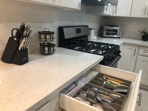 Fully stocked kitchen with spices, utensils, silverware, and cutlery.
