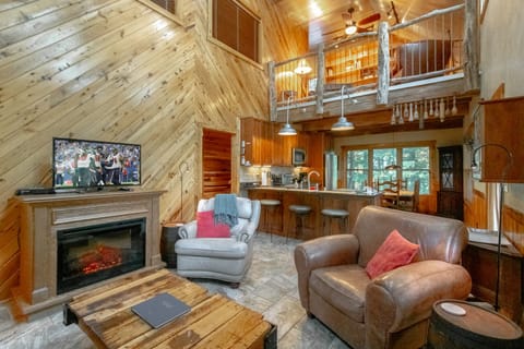 Kitchen and dining area open to the living room with electric fireplace and loft above