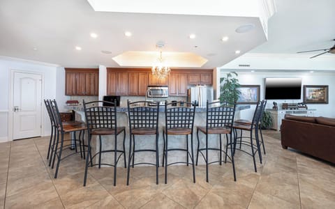 The kitchen features wood cabinets, a granite countertop, and a breakfast bar with stylish seating, perfect for gatherings