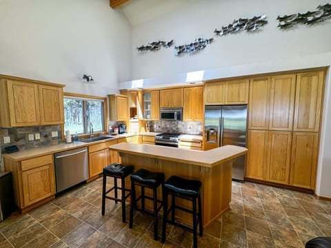Cook and connect in this spacious kitchen featuring modern stainless steel appliances, ample counter space, and bar seating for three. A perfect space for preparing meals and gathering with loved ones