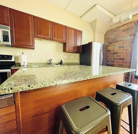 Granite Bar & Seating
This spacious granite island provides extra seating for casual meals or entertaining. Industrial barstools, exposed brick, and warm wood tones create a stylish yet comfortable vibe.