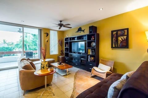 Living room has comfortable couches, a flat screen TV, and a balcony with ocean views