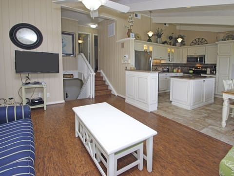 Kitchen with new cabinets, appliances, and stone flooring. Living area has wood.