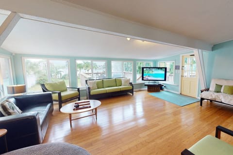Large Living room area with plenty of seating, wide open windows looking out towards the Bay, and a large TV.