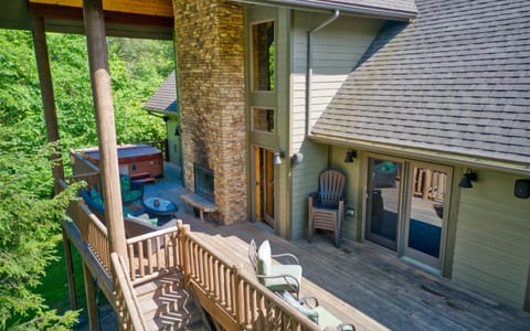 Expansive back deck with fireplace and hot tub next to each other.