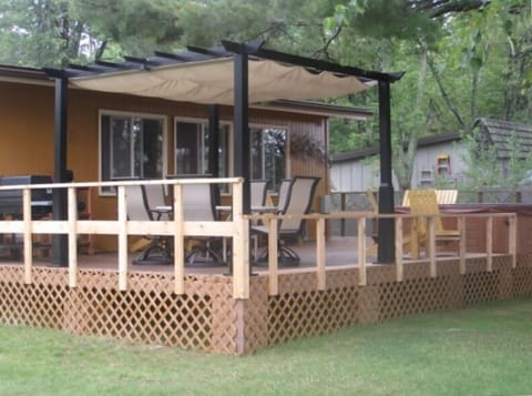 Shaded eating area on the deck with a gas grill and hot tub.