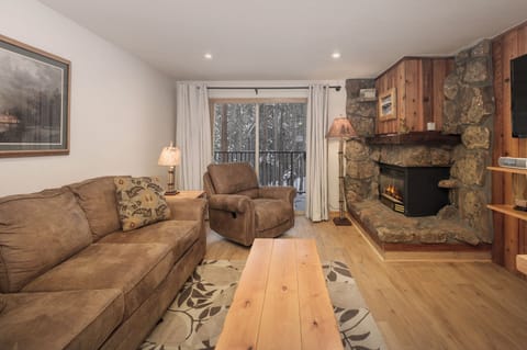 Cozy up in this warm living room where plush seating meets rustic stone fireplace charm—your perfect retreat after mountain adventures.