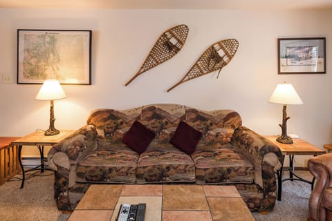 Settle into your cozy mountain retreat where rustic charm meets comfort, complete with vintage snowshoes and warm lighting for perfect evening relaxation.
