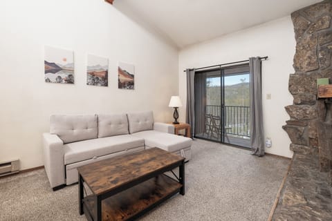 Unwind on your plush sectional sofa while mountain views fill the window. The stone fireplace adds rustic charm to this serene retreat.