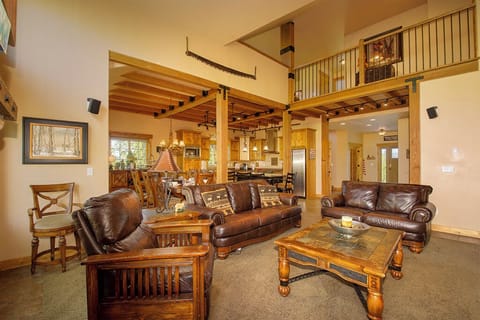 Relax in your spacious great room featuring rich leather seating, exposed beam ceilings, and a stunning loft overlooking the open kitchen.