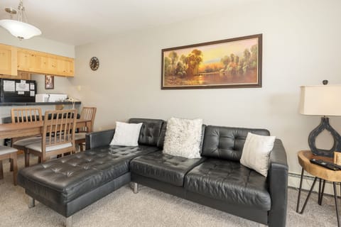 Relax on plush leather seating in your open-concept living space, where modern comfort meets rustic charm with warm wood accents.