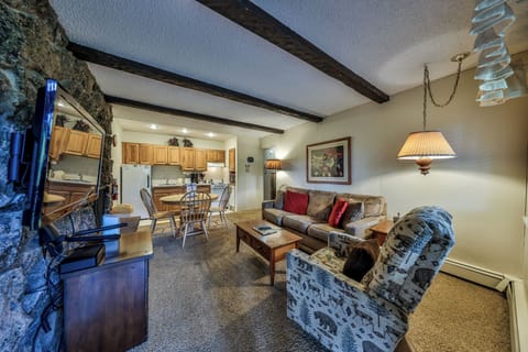 Relax in your cozy living space with exposed beams, stone fireplace, and fully equipped kitchen—perfect for mountain retreat evenings.