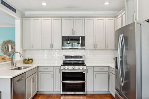 Your fully equipped kitchen features modern stainless steel appliances and crisp white cabinetry, perfect for preparing memorable meals during your stay.