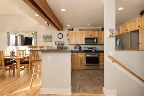 View of kitchen, counter, dining, rustic hardwood floors.
