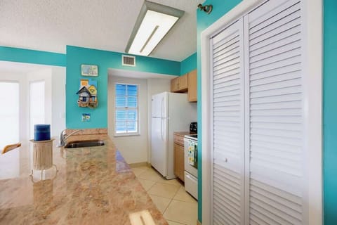 A fully equipped kitchen includes a refrigerator/freezer, kitchen sink, a stove, silverware, dishware, cookware, and basic cooking utensils, and some dish cleaning supplies, like a drain rack, dish soap, a sponge and paper towels, and cabinetry.