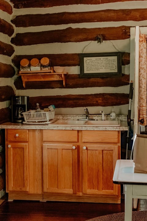 Coffee pot and kitchen sink with supplies underneath 
